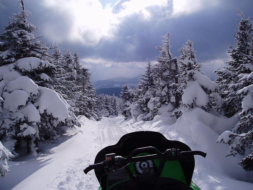 A snowmobile trail through snow-covered spruce in the Rangeley Lakes region